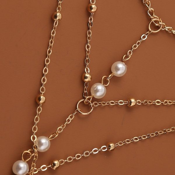 Bracelet bague avec chaînes dorés et perles blanches