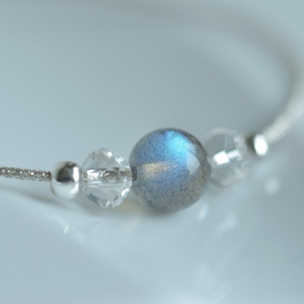 Bracelet labradorite avec une perle ronde bleue posé sur un fond gris.